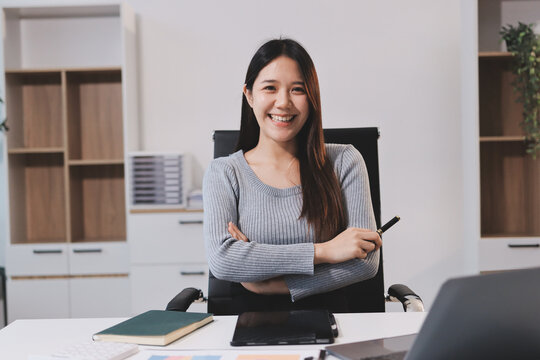 young woman is working on laptop in modern office environment, showcasing focused and productive atmosphere. She is dressed in professional white shirt, with coffee cup and small plant on table,