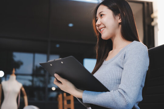 young woman is working on laptop in modern office environment, showcasing focused and productive atmosphere. She is dressed in professional white shirt, with coffee cup and small plant on table,