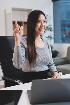 young woman is working on laptop in modern office environment, showcasing focused and productive atmosphere. She is dressed in professional white shirt, with coffee cup and small plant on table,
