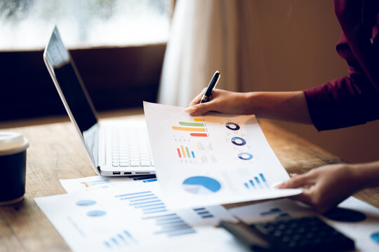 Business professional reviewing financial reports and analyzing charts at a desk, representing accounting, financial planning, data analysis and business management.