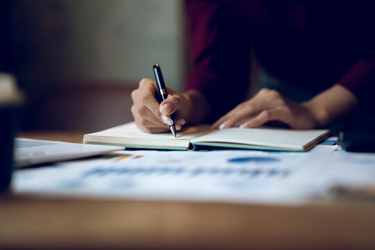 Business professional reviewing financial reports and analyzing charts at a desk, representing accounting, financial planning, data analysis and business management.