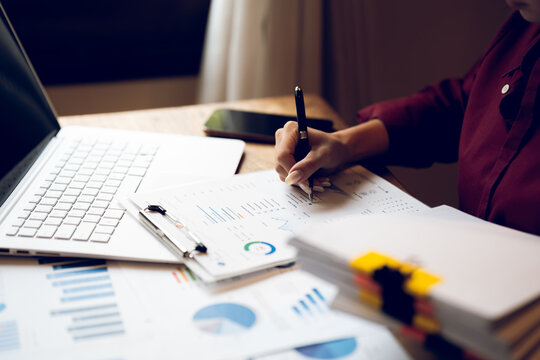 Business professional reviewing financial reports and analyzing charts at a desk, representing accounting, financial planning, data analysis and business management.