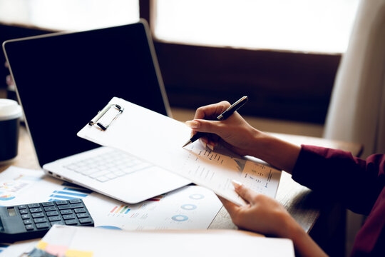 Business professional reviewing financial reports and analyzing charts at a desk, representing accounting, financial planning, data analysis and business management.