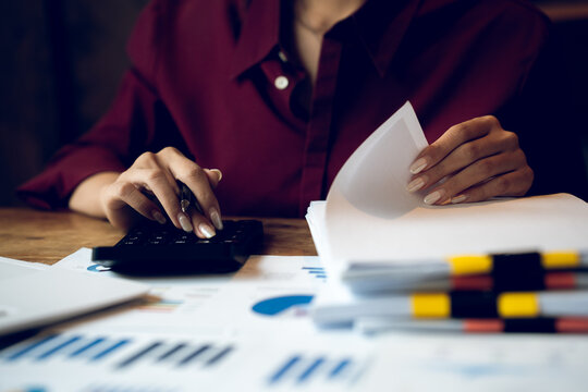 Business professional calculating financial data while reviewing charts and reports, representing accounting, budgeting, investment analysis and financial planning.
