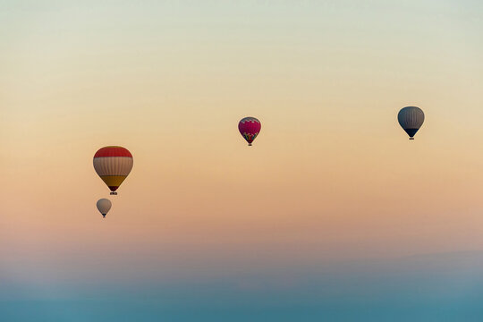 Four hot air balloons drifting through a soft gradient morning s