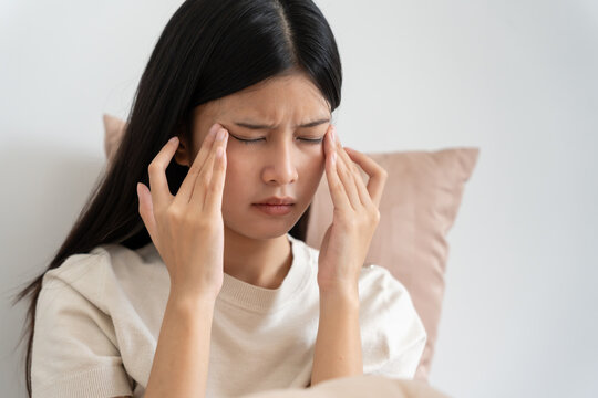 Headache, female having migraine pain, bad health, Asian woman feeling stress and headache, Office syndrome, sad tired touching forehead having migraine or depression, irritated girl, sadness grief