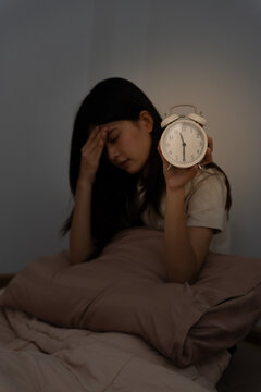 asian woman in bed late trying to sleep suffering insomnia, sleepless or scared in a nightmare, looking sad worried and stressed. Tired and headache or migraine waking up in the middle of the night.