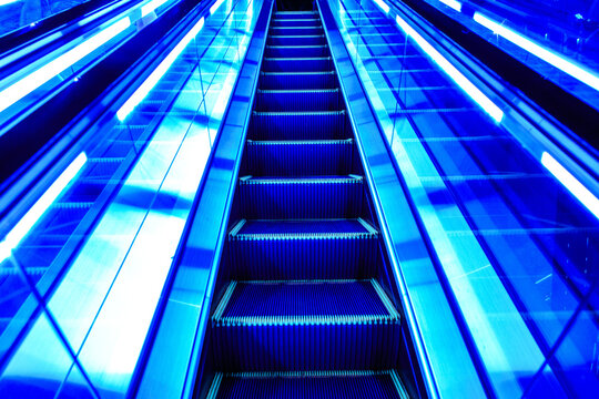 Futuristic neon blue glowing escalator moving upward in modern Tokyo building, symbolizing progress, career advancement, and technology.