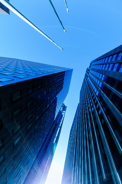 Dynamic upward view of corporate office towers with sunlight flare in Tokyo, symbolizing ambition and business success.