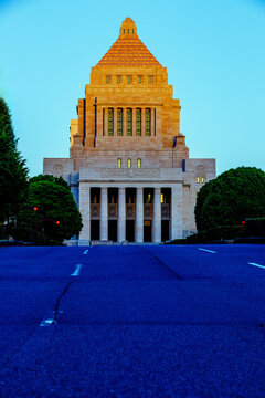 Symmetrical low-angle perspective of the National Diet Building in Tokyo under a clear morning blue sky, symbolizing Japanese politics and law.