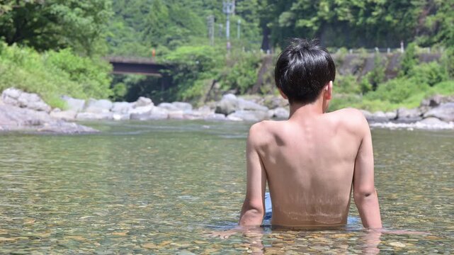 夏の清流に浸かって水遊びを楽しむ少年の後ろ姿の顔無し動画