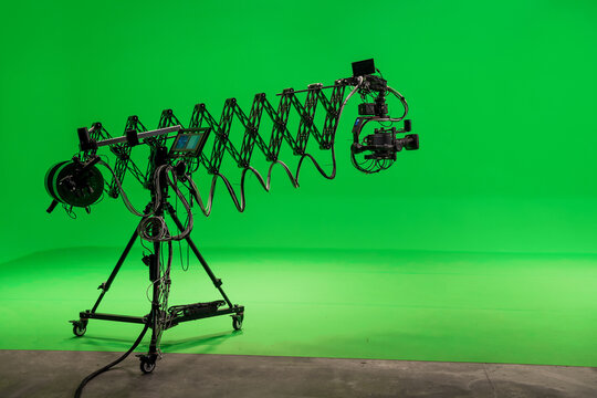 Camera on telescopic jib crane against green background. Empty TV studio interior with green screen. Video production with background replacement.