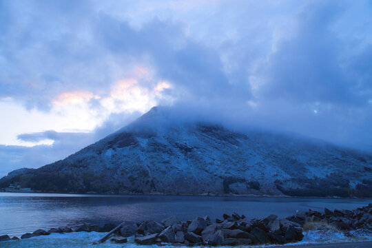 Snow-Covered Mountain in Fog by a Nordic Fjord