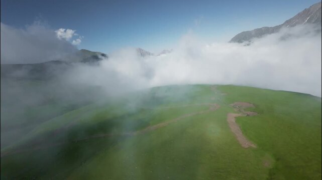 Aerial view of lush green landscape with clouds rolling over mountains