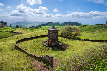 Fototapeta premium Traditional stone water fountain on green rolling hills in Sao Miguel Island Azores Portugal