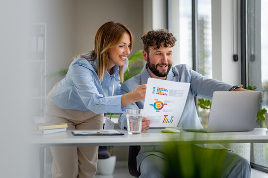 Colleagues discuss project data using charts and graphs in an office setting during the day