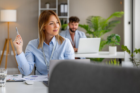 Business meeting in modern office with a woman thinking and a man working on a laptop in background