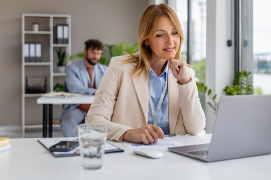 Business meeting at office with woman using laptop and man working in background