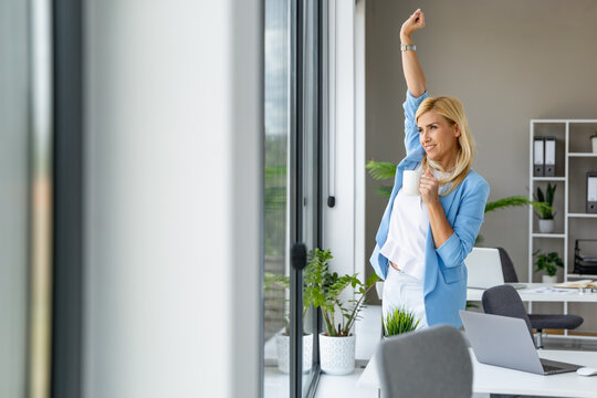 Woman stretching by the window in a modern office space during the afternoon