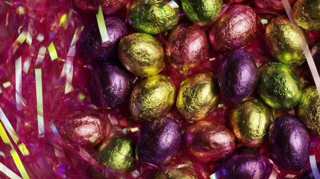 Assorted foil eggs rotating in pink tinsel nest