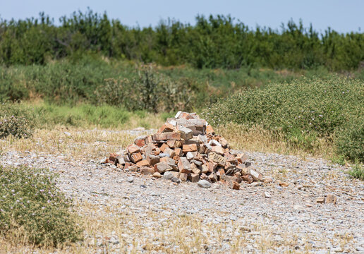 Stacked bricks form a mound on gravel ground