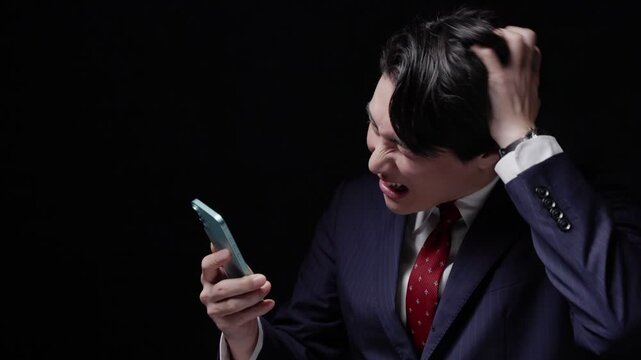 スマホを見て頭を抱えるビジネスマン男性