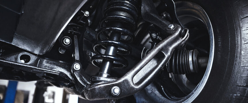 Car suspension system with coil spring and control arm in a vehicle repair shop.