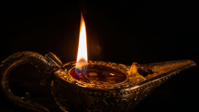 Ancient metallic oil lamp with a bright flickering flame in dark atmosphere mysterious traditional decoration oriental spiritual meditation stillness lighting cultural craftsmanship