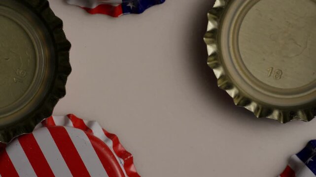 American flag bottle caps scattered on white surface