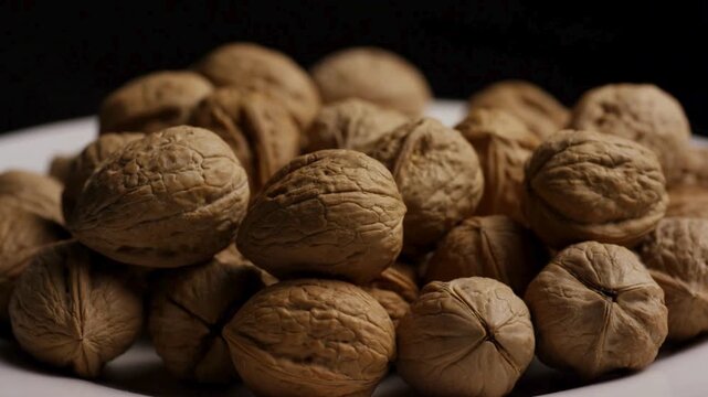 Pile of whole walnuts rotating against black background