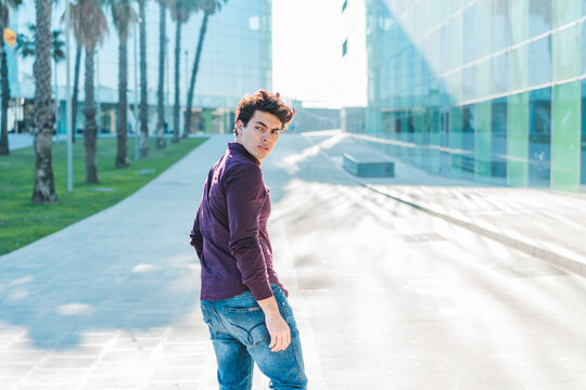 Serious young man walking in the city turning round