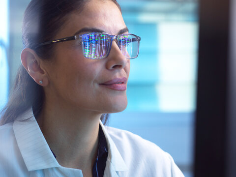 Scientist analyzes genomic data reflected in her glasses