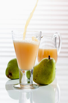 Carafe and glass pouring with pear juice, close up