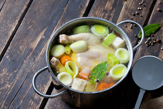 Cooking pot with raw corn-fed chicken, onion, herbs and greens
