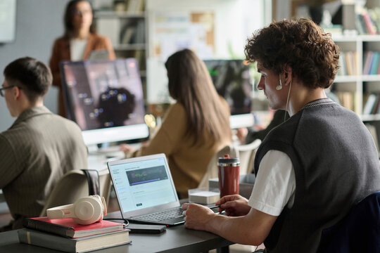 A young man programs on a laptop while studying at the university