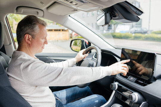Driver touching infotainment system on dashboard in automobile