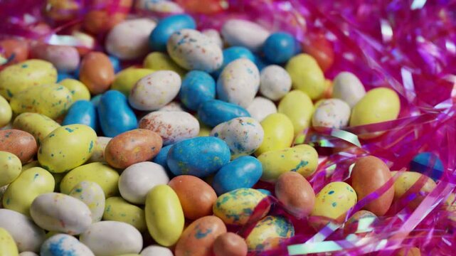 Colorful speckled easter egg candies in pink shredded tinsel