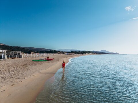 Woman in red swimsuit walks on the beach during summer vacation
