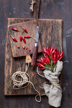 Bunch of red chili peppers, cord and knife on wooden boards