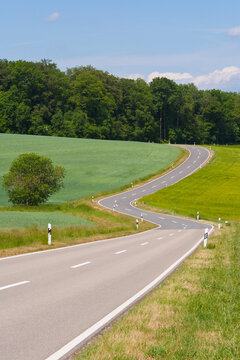 A twisting country road crosses green fields near Weikersheim