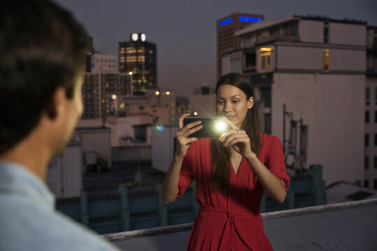 Young woman taking pictures of friends at a rooftop party