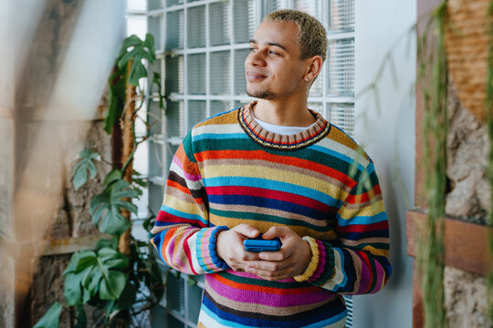 A smiling businessman holds a phone in a modern office