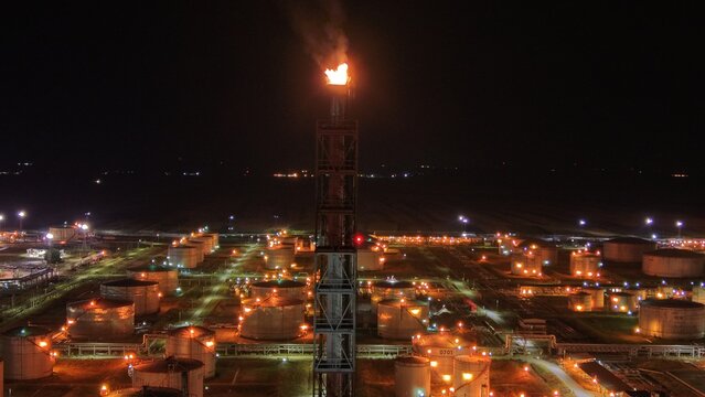 Aerial view of the oil refinery flare stack burning at night in the industrial zone with illuminated storage tanks in Pancevo, Serbia.