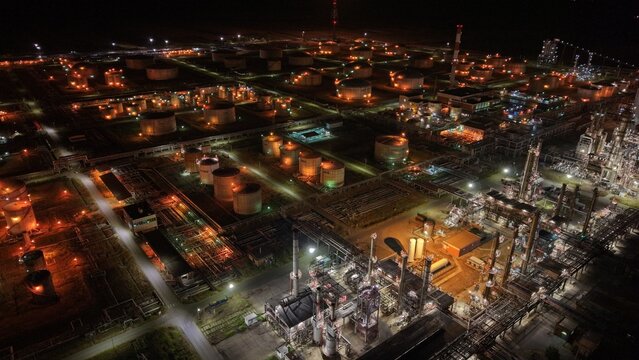 Aerial view of the South industrial zone oil refinery at night with illuminated storage tanks and complex industrial infrastructure in Pancevo, Serbia.