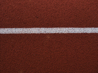 Fototapeta premium Red synthetic rubber running track surface marked with crisp white lane lines.