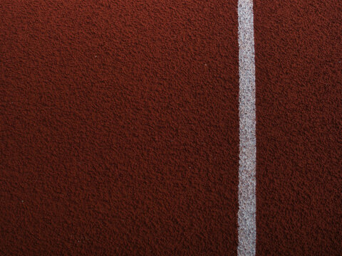 Red synthetic rubber running track surface marked with crisp white lane lines.