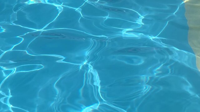 Bright blue water ripples in a swimming pool under the sun on a clear afternoon