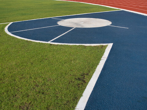 Sports throwing circle features a blue and white surface the area for the shot put or hammer throw is surrounded by a green field and a running track.