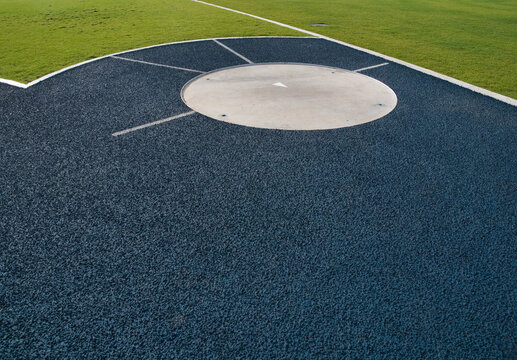 Sports throwing circle features a blue and white surface the area for the shot put or hammer throw is surrounded by a green field and a running track.