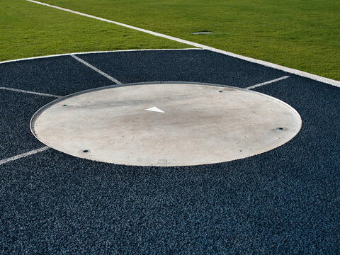 Sports throwing circle features a blue and white surface the area for the shot put or hammer throw is surrounded by a green field and a running track.
